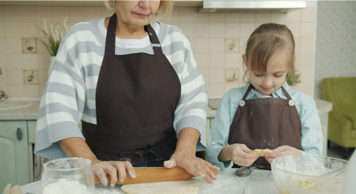 Avó e neta cozinhando juntas, mãos de gerações diferentes em atividade cotidiana